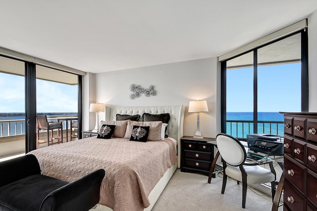 carpeted bedroom with floor to ceiling windows, a water view, and multiple windows