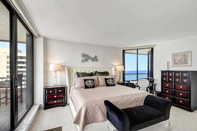 bedroom with access to exterior, a water view, and light colored carpet