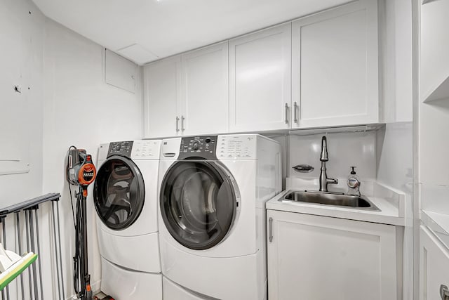 clothes washing area featuring washer and clothes dryer, cabinets, and sink