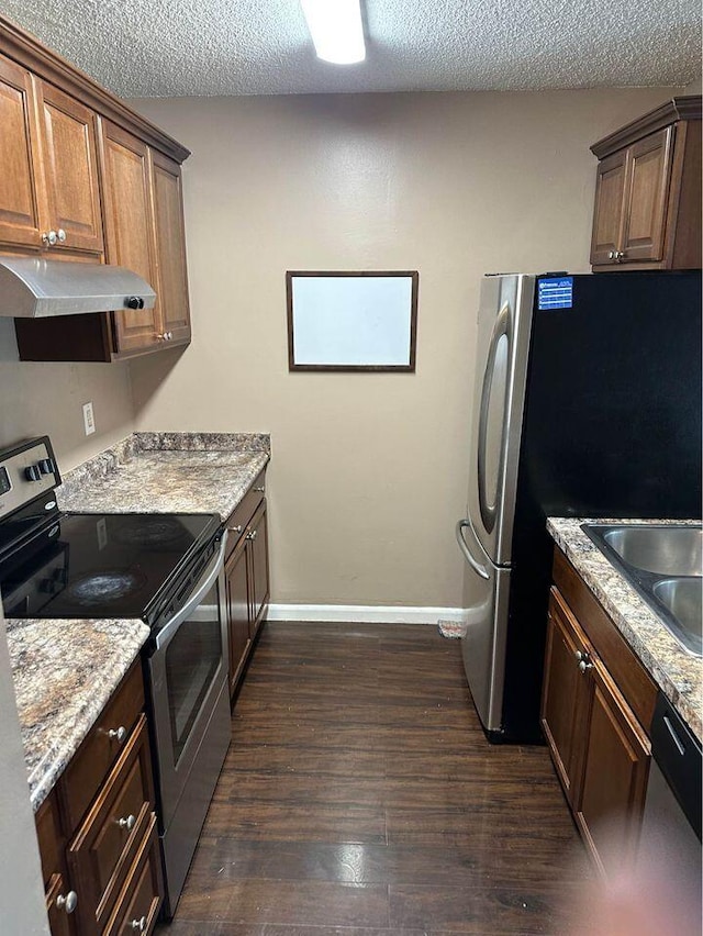 kitchen with stainless steel appliances, a textured ceiling, dark hardwood / wood-style flooring, light stone counters, and sink