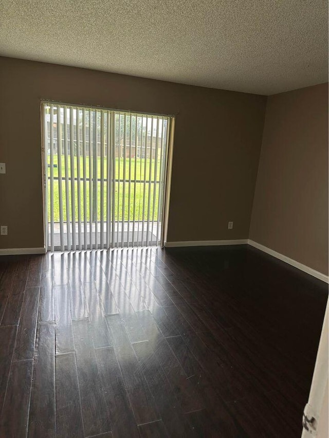 empty room featuring a textured ceiling and dark hardwood / wood-style floors