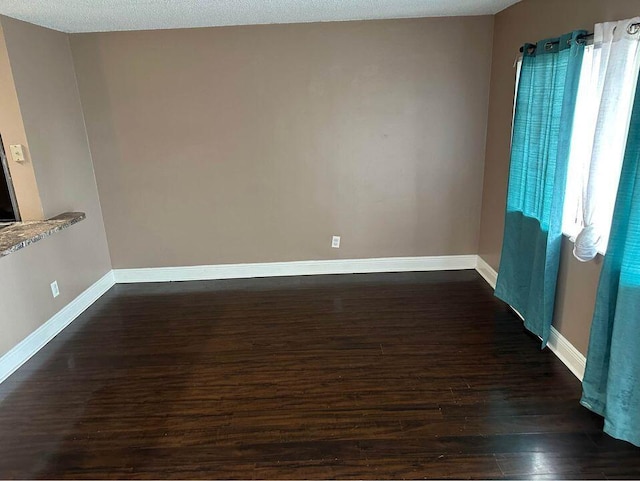 empty room with a textured ceiling, dark hardwood / wood-style floors, and a wealth of natural light