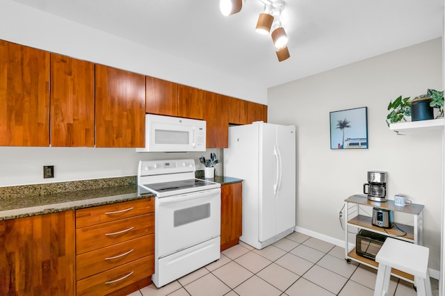 kitchen featuring light tile flooring, white appliances, dark stone countertops, and track lighting