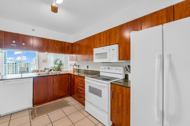 kitchen featuring white appliances, sink, light tile floors, and dark stone countertops