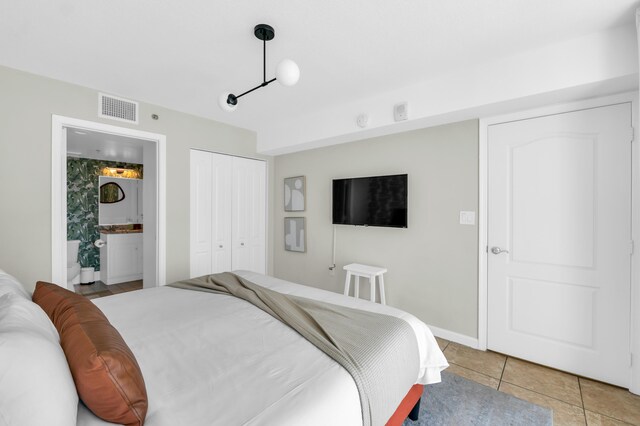 tiled bedroom featuring connected bathroom and a closet