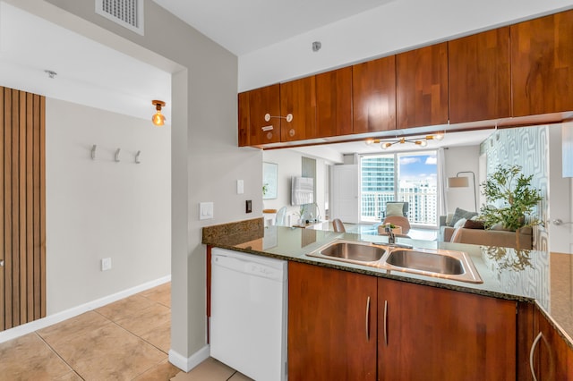 kitchen featuring kitchen peninsula, sink, dark stone counters, white dishwasher, and light tile flooring