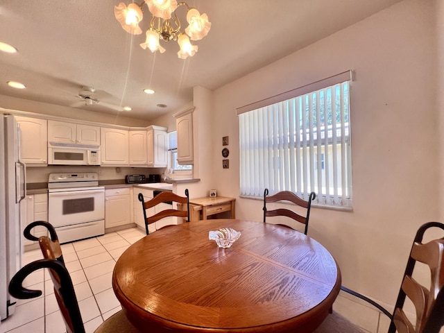 dining room featuring ceiling fan with notable chandelier, light tile patterned floors, and sink