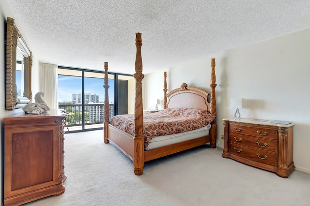 bedroom featuring access to outside, a textured ceiling, a wall of windows, and light colored carpet