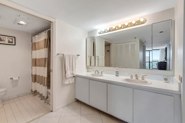 bathroom with toilet, tile floors, dual sinks, and large vanity