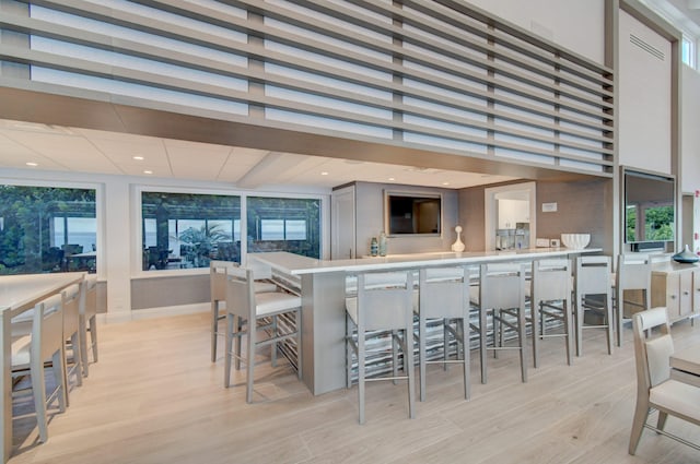 kitchen with a high ceiling, a wealth of natural light, a breakfast bar area, and light hardwood / wood-style flooring