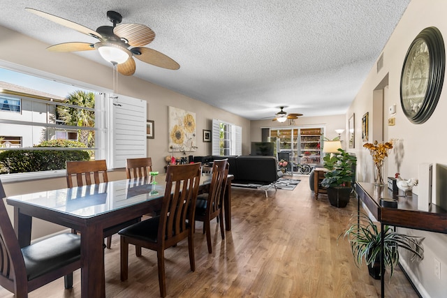 dining space with a textured ceiling, ceiling fan, and hardwood / wood-style floors