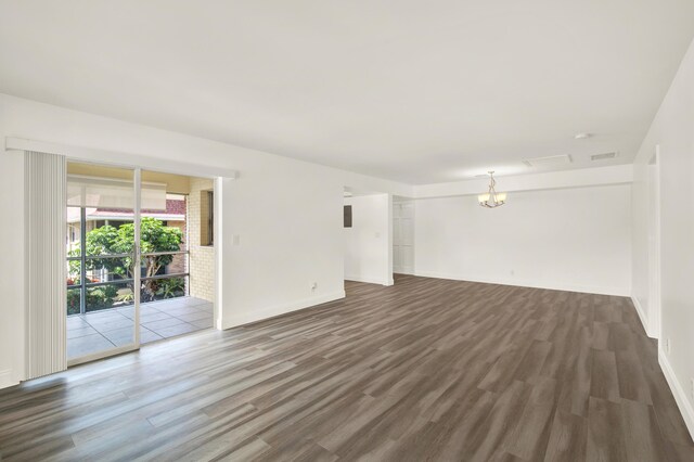 empty room with a notable chandelier and dark hardwood / wood-style flooring