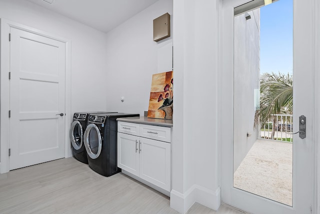 washroom featuring cabinet space, light wood finished floors, and washing machine and clothes dryer