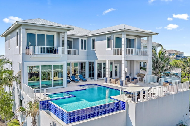 rear view of house featuring a patio, metal roof, fence, a pool with connected hot tub, and stucco siding