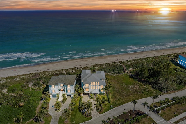 aerial view at dusk featuring a water view and a view of the beach