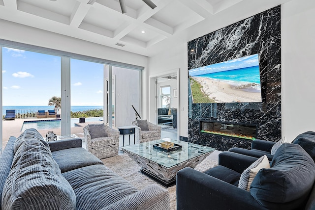 living room featuring visible vents, coffered ceiling, a premium fireplace, a water view, and beam ceiling