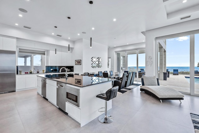 kitchen featuring visible vents, dark countertops, modern cabinets, stainless steel appliances, and a sink