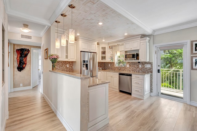 kitchen with light stone countertops, decorative light fixtures, sink, light hardwood / wood-style flooring, and stainless steel appliances