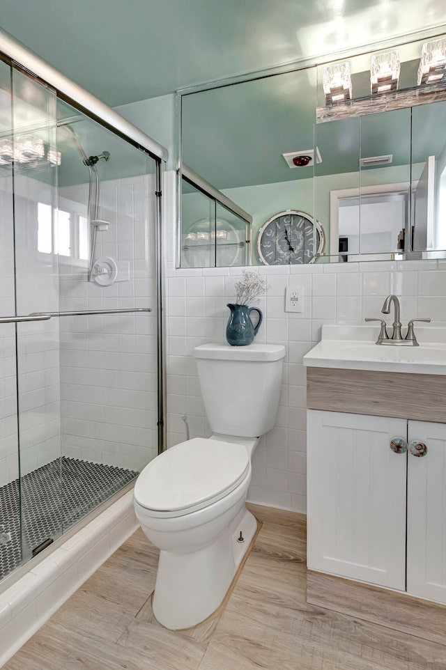 bathroom featuring tile walls, toilet, a shower with door, backsplash, and vanity