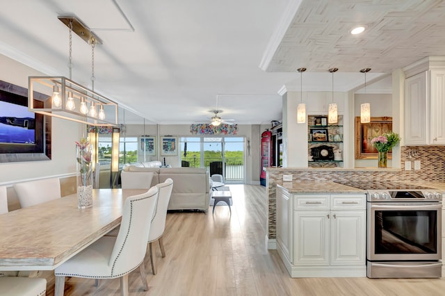 kitchen with stainless steel electric stove, tasteful backsplash, ceiling fan with notable chandelier, and pendant lighting