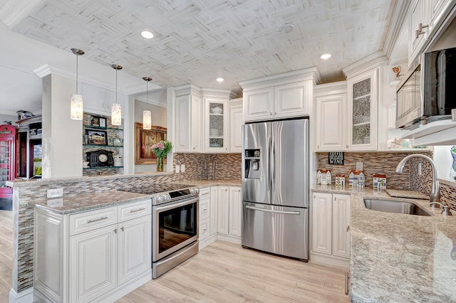 kitchen featuring kitchen peninsula, tasteful backsplash, appliances with stainless steel finishes, hanging light fixtures, and sink