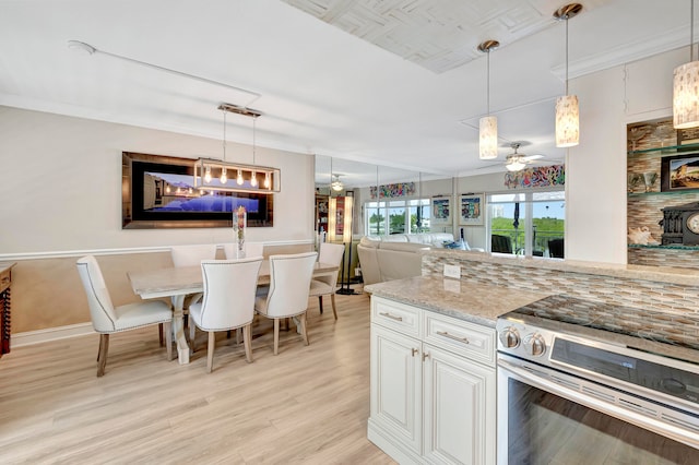 kitchen featuring pendant lighting, stainless steel electric range oven, ceiling fan, and white cabinetry