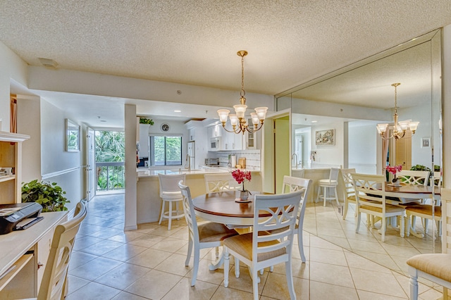 dining room with a textured ceiling, light tile floors, and an inviting chandelier