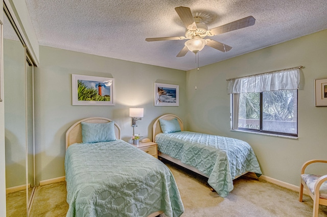 bedroom featuring light colored carpet, a textured ceiling, ceiling fan, and a closet