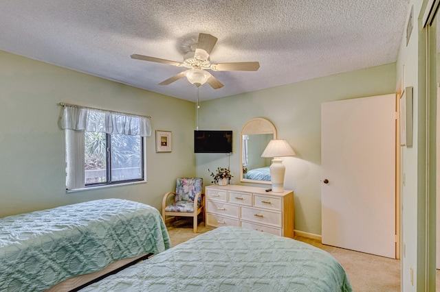 bedroom featuring light colored carpet, a textured ceiling, and ceiling fan