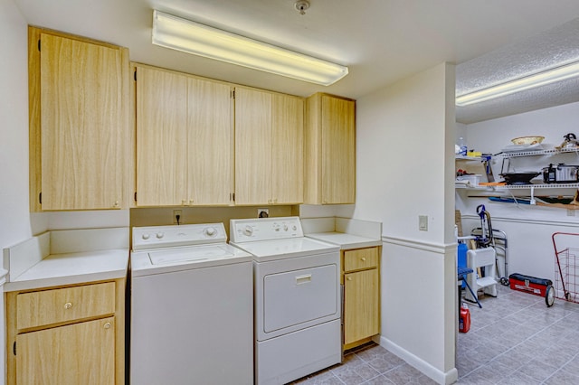 clothes washing area featuring cabinets, washer and dryer, and light tile floors