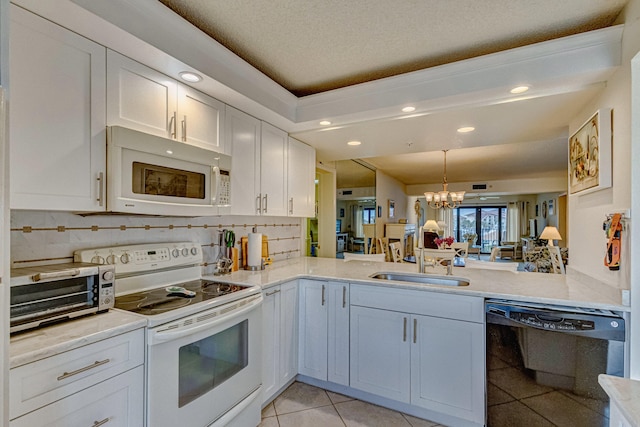 kitchen featuring white appliances, tasteful backsplash, kitchen peninsula, and an inviting chandelier