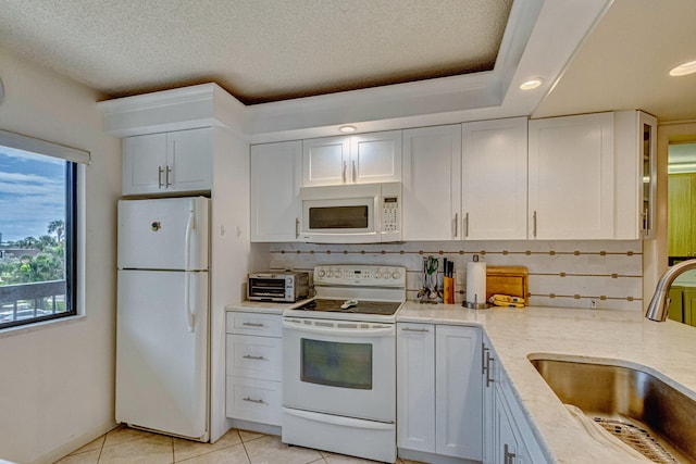 kitchen with light tile floors, white cabinets, sink, white appliances, and tasteful backsplash