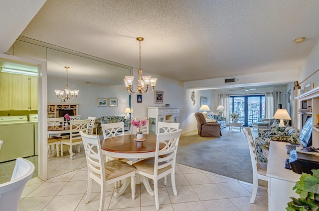 tiled dining room featuring a chandelier, separate washer and dryer, and a textured ceiling