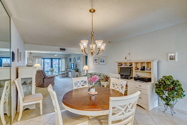 dining room with ceiling fan with notable chandelier, light tile floors, and a textured ceiling