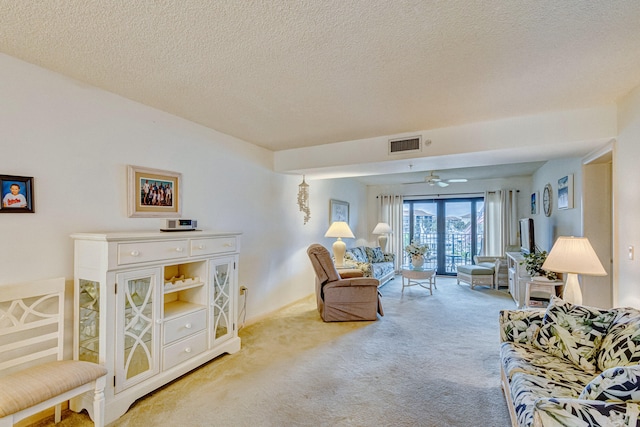 carpeted living room featuring a textured ceiling and ceiling fan