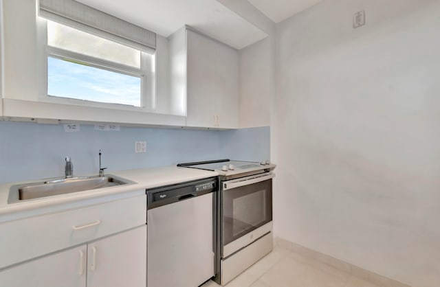 kitchen featuring light tile floors, stove, white cabinets, dishwasher, and sink