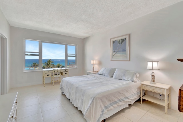 tiled bedroom with a textured ceiling and a water view