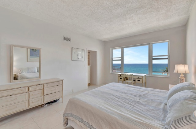 tiled bedroom with a textured ceiling and a water view