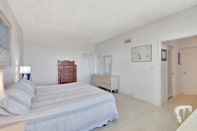 bedroom with a textured ceiling and light tile floors