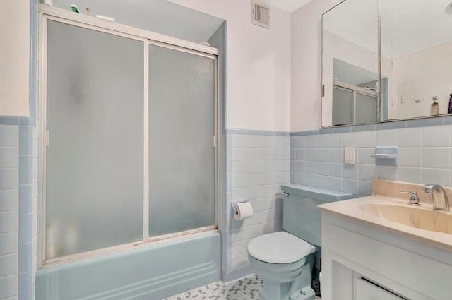 full bathroom featuring tile walls, enclosed tub / shower combo, toilet, and tile floors