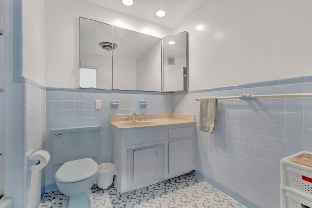 bathroom with vanity, tile flooring, toilet, and tile walls