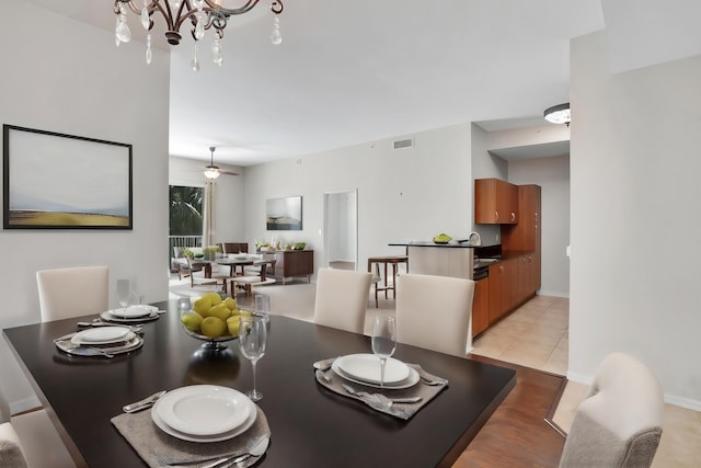 tiled dining area featuring ceiling fan with notable chandelier