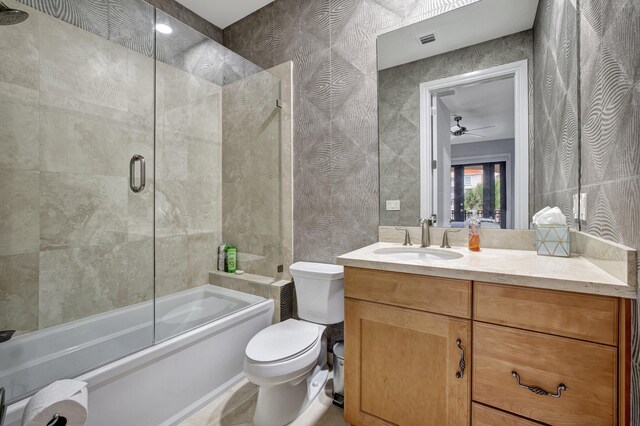 full bathroom with ceiling fan, bath / shower combo with glass door, vanity, and toilet