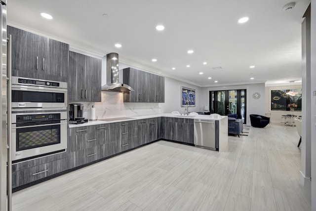 kitchen with kitchen peninsula, wall chimney exhaust hood, light hardwood / wood-style flooring, stainless steel appliances, and crown molding