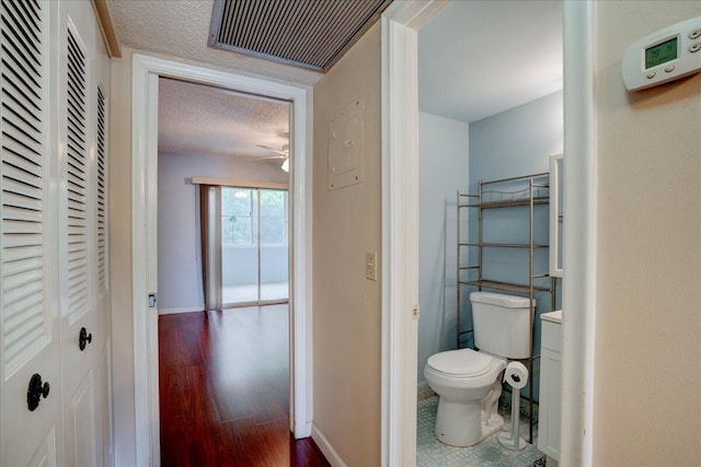 bathroom featuring toilet, hardwood / wood-style flooring, ceiling fan, and a textured ceiling