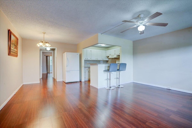 unfurnished living room with ceiling fan with notable chandelier, hardwood / wood-style flooring, and a textured ceiling