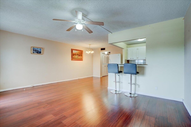 unfurnished living room with a textured ceiling, ceiling fan with notable chandelier, and light wood-type flooring