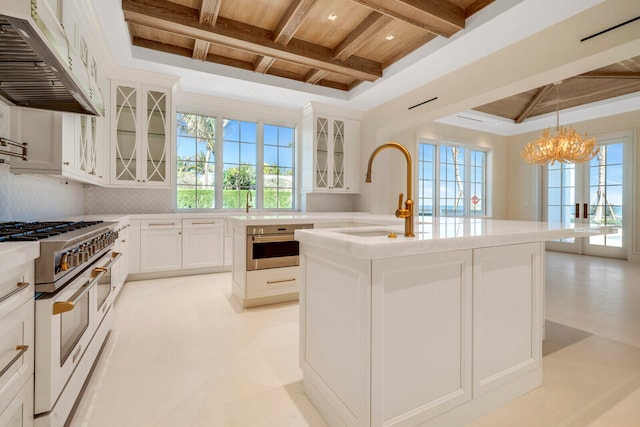 kitchen with white cabinetry, double oven range, a kitchen island with sink, and premium range hood