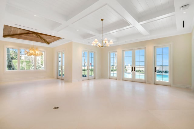 unfurnished room with a notable chandelier, coffered ceiling, french doors, and a wealth of natural light