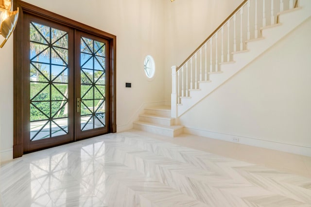 entryway with french doors, light parquet flooring, and a towering ceiling